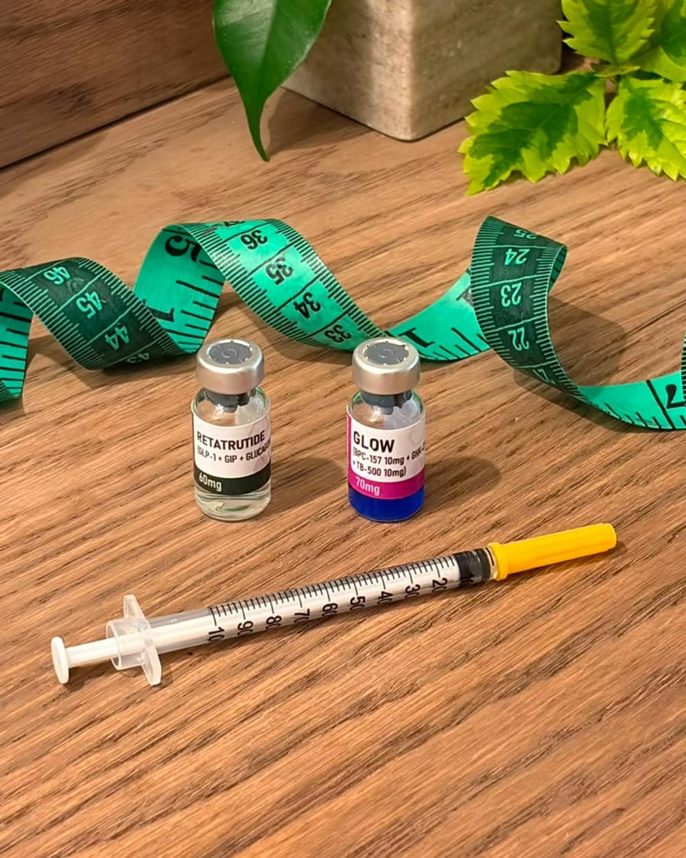 Viales de medicamento y jeringa de insulina sobre un escritorio, junto a una cinta métrica